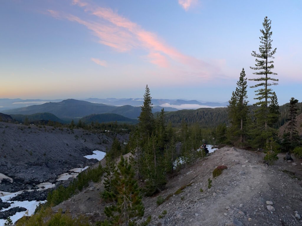 A sunrise view from Mt. St. Helens' Monitor Ridge summit route, overlooking distant mountains and a crowd-free hiking trail.