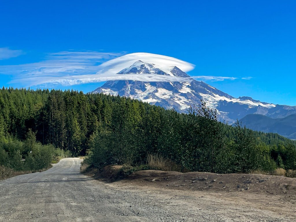 Mt. Rainier under a lenticular cloud with a dirt road in the foreground, highlighting an off-the-beaten-path and how to avoid crowds in the outdoors.