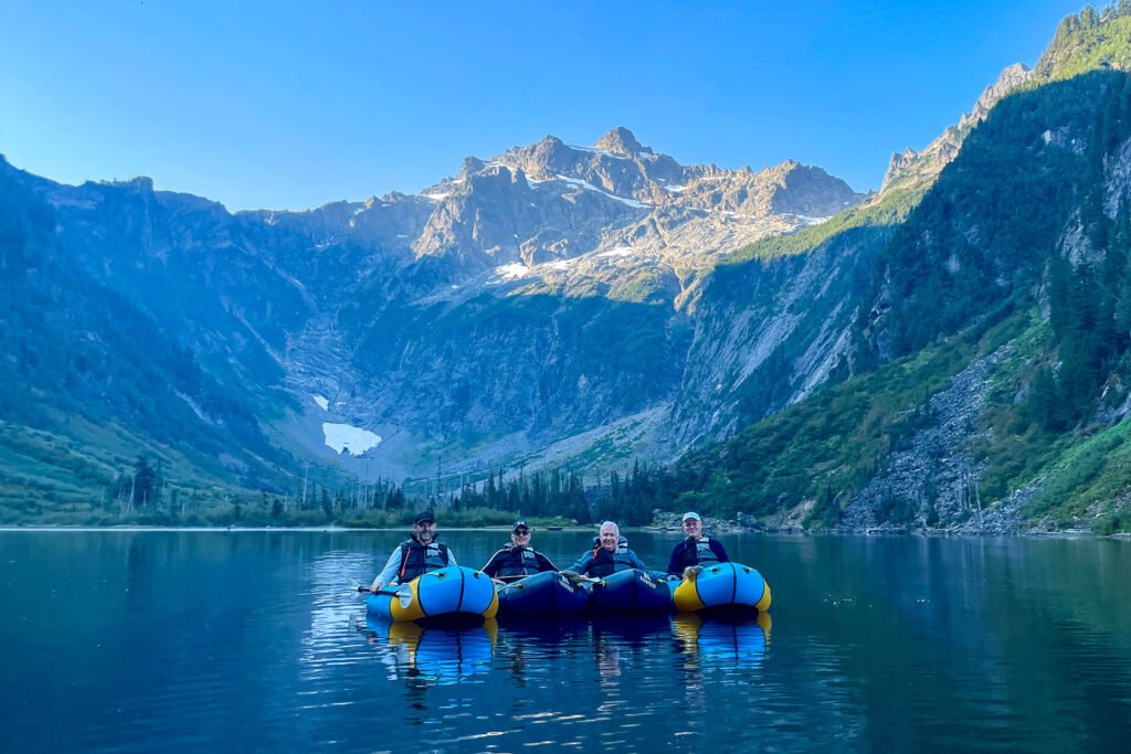 Four men alpine lake packrafting on Optimum Adventures' alpine lake Overnight Tour.