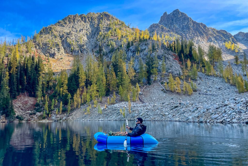 Optimum Adventures rental customer packrafting Blue Lake alpine lake during Larch Madness in Washington.
