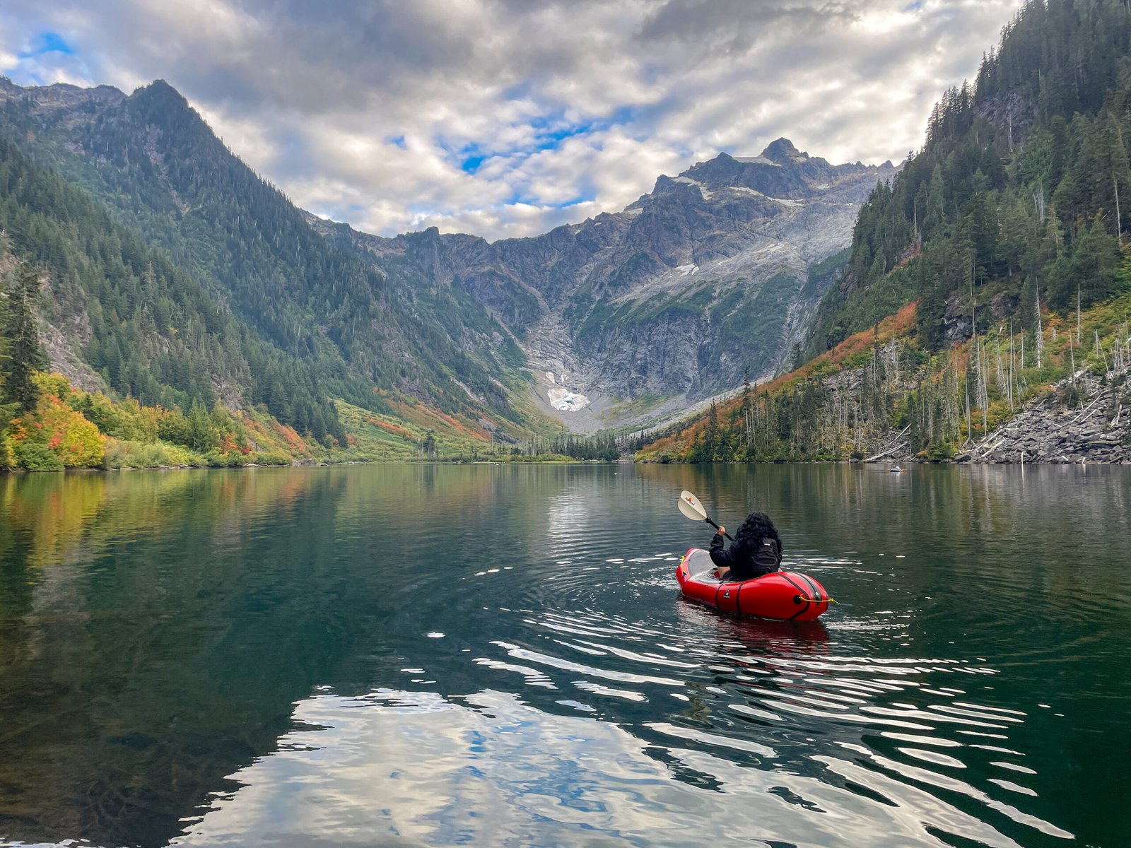 A guest paddling an Alpacka Expedition packraft from shore toward the glacier on Goat Lake during the Optimum Adventures Goat Lake tour in Washington.