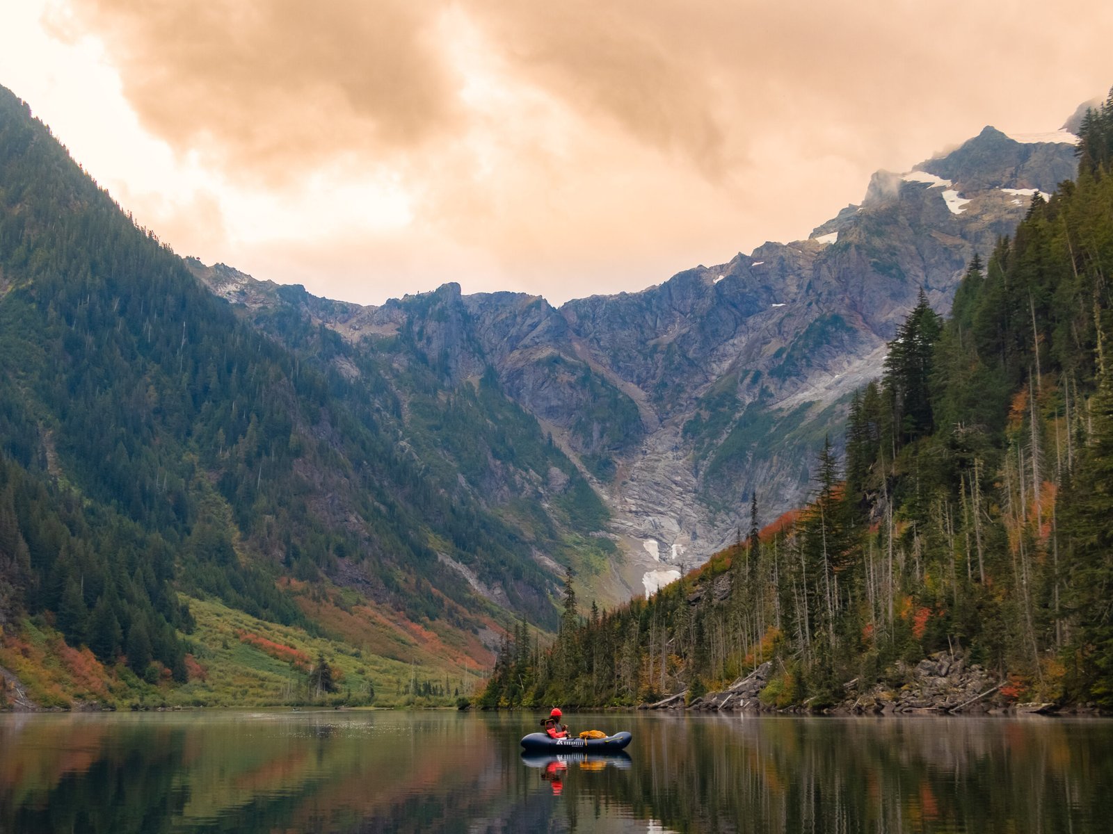A guest paddling a Kokopelli Hornet-Lite packraft on Goat Lake with towering Cascade peaks and a glacier behind her during the Optimum Adventures Goat Lake tour.