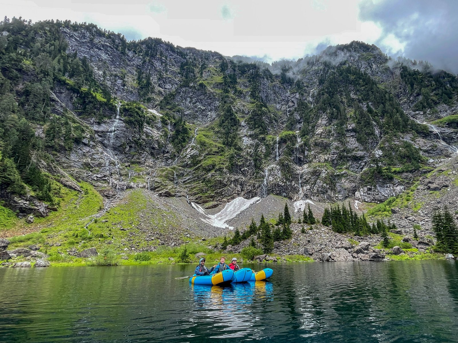 Guests and their guide posing together on the Lake 22 tour with waterfalls, alpine scenery, and the surrounding Cascade Mountains behind them.