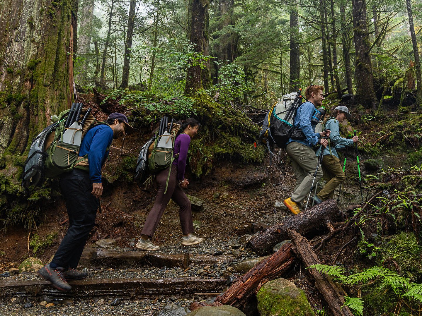 Guests hiking the Lake 22 Trail with their guide while carrying hiking and packrafting equipment during the Optimum Adventures Lake 22 tour.