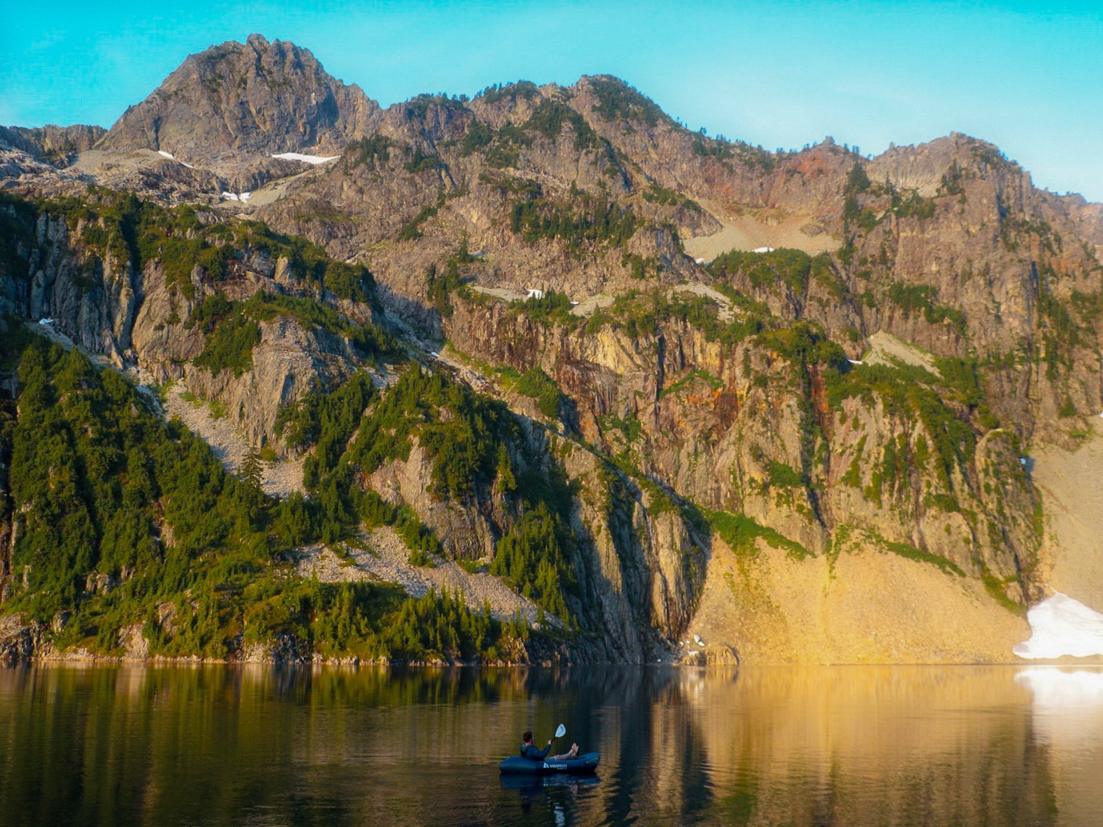 Adam Jones, founder of Optimum Adventures, paddling a Kokopelli Hornet-Lite packraft across Snow Lake during a paddle on a Snow Lake Tour in Washington.
